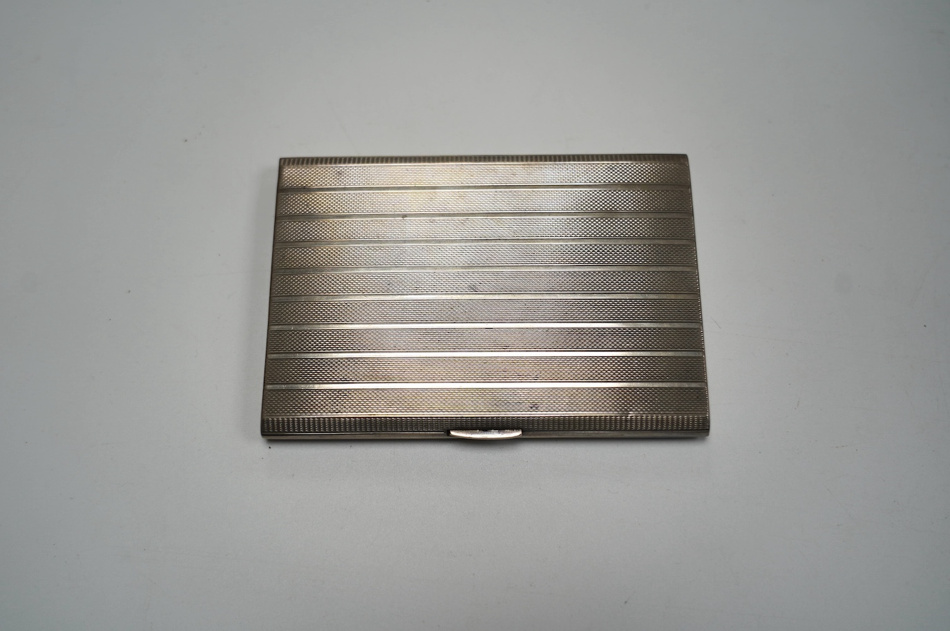 A George V engine turned silver cigarette case, Birmingham, 1945, 12.4cm, 6.5oz. Condition - fair